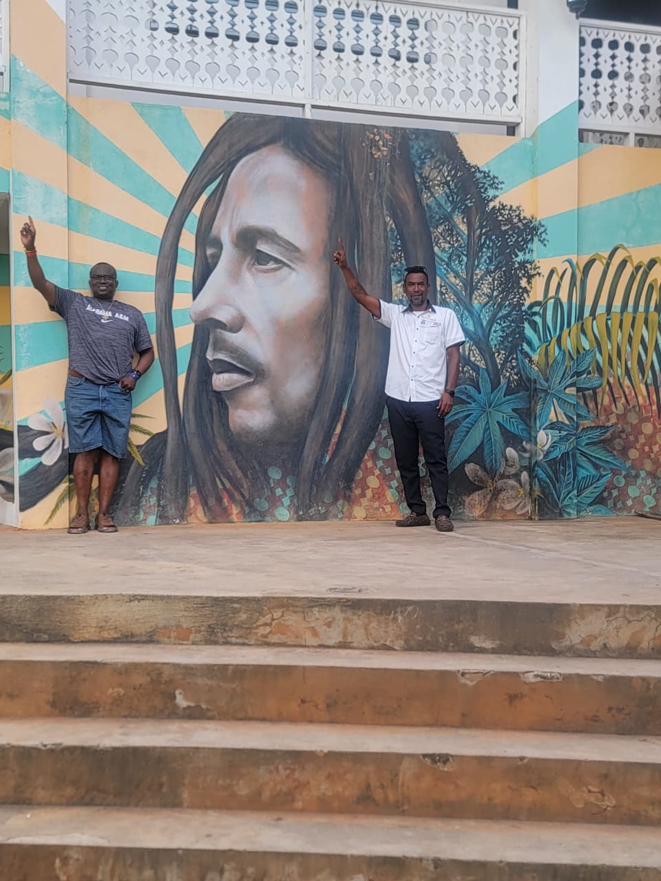 Guests beside a Bob Marley mural